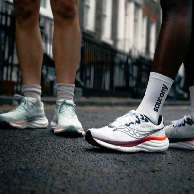 Nahaufnahme der Saucony Ride 19 Laufschuhe in Mint und Weiß auf Asphalt.