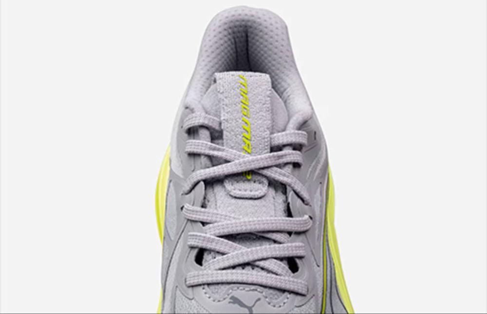 Nahaufnahme der Schnürung und der gepolsterten Zunge des grauen Puma Magmax Nitro mit neongelbem Logo.