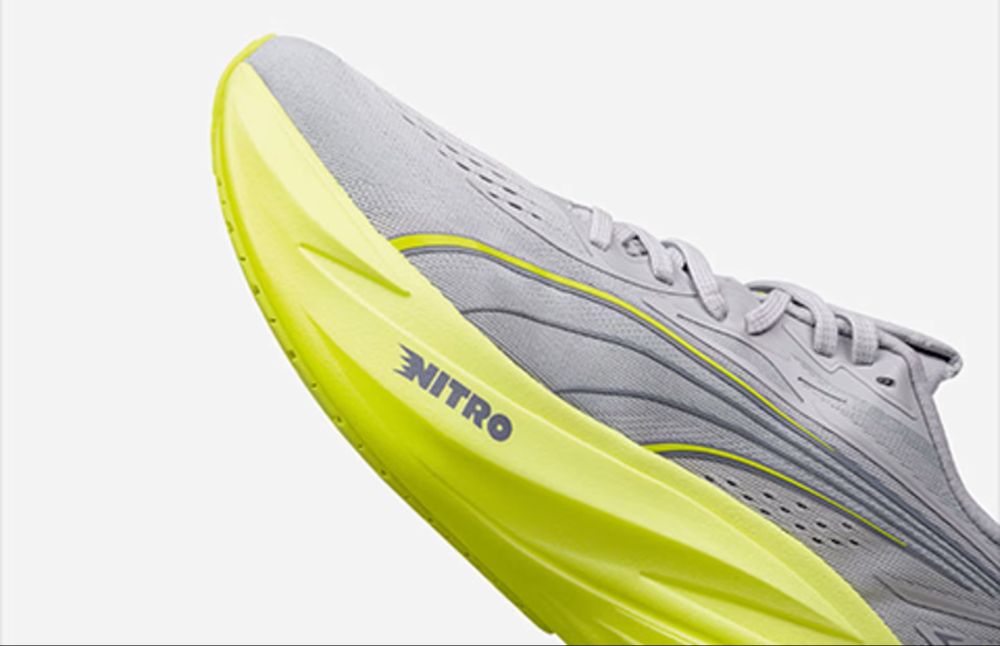 Nahaufnahme des grauen Puma Magmax Nitro Laufschuhs mit Fokus auf der neongelben NITRO-Dämpfungssohle.