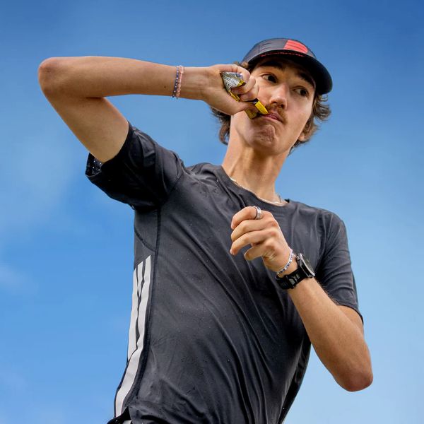 Sportler nutzt Sporternährung beim Laufen: Läufer isst einen Energieriegel zur Regeneration und Energieversorgung während des Trainings im Freien