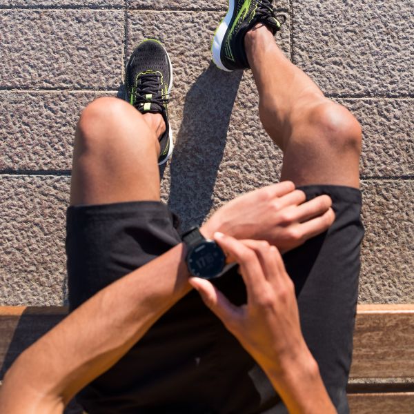 Läufer nutzt Smartwatch zur Trainingsanalyse, kombiniert mit Brooks Laufschuhen und kurzer Sporthose